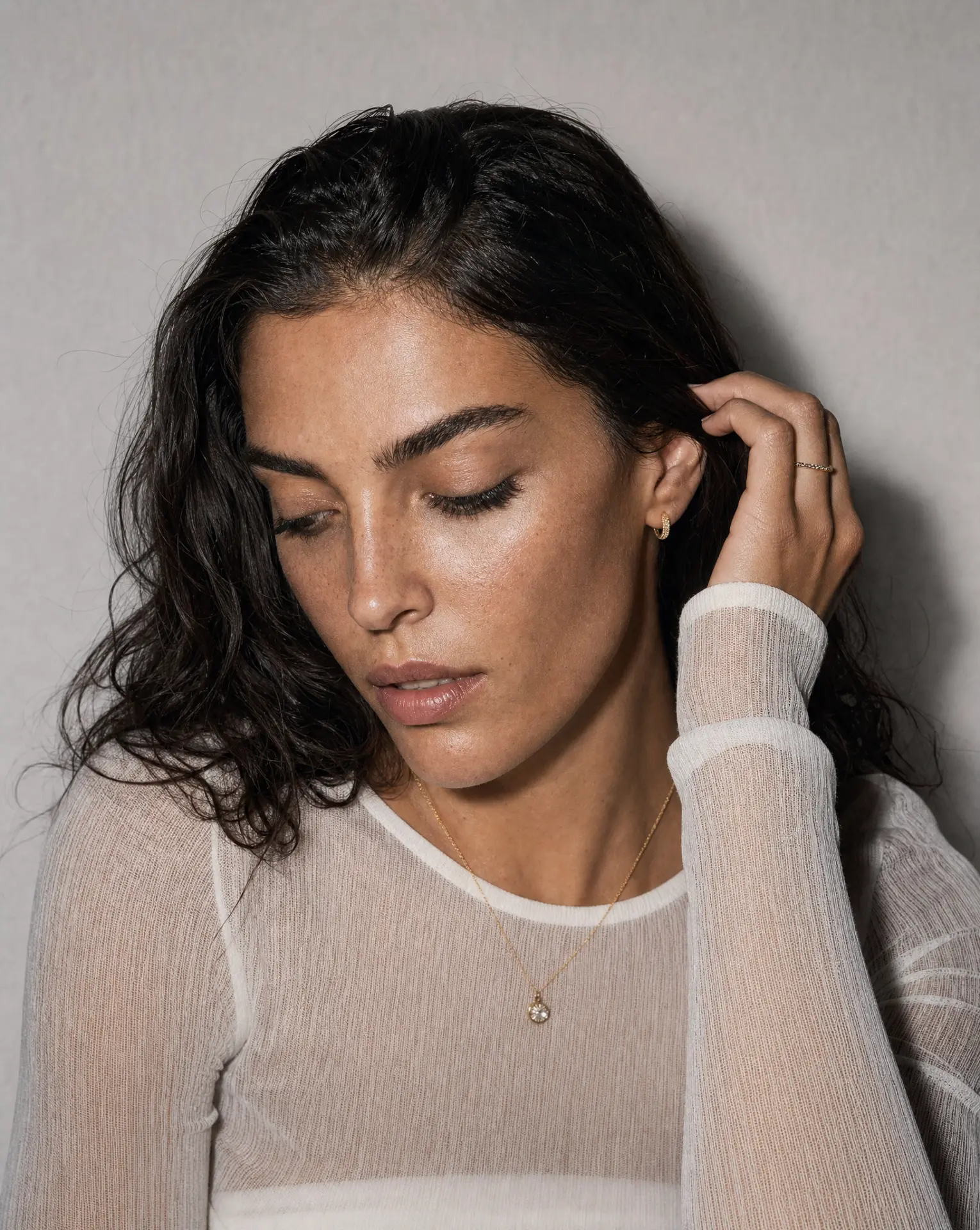 Candid portrait with gold hoop earring, pendant necklace and fine ring