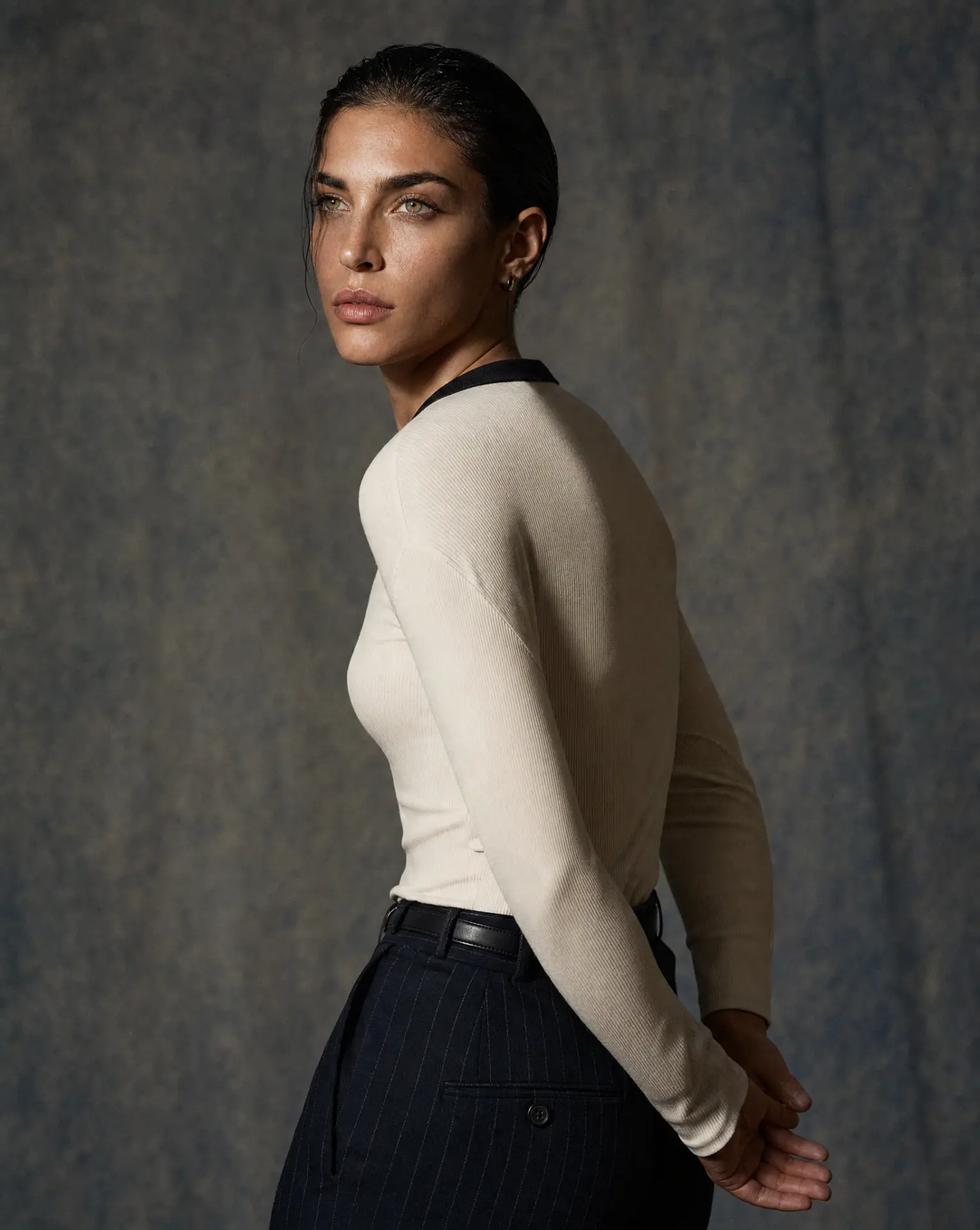 Womenswear cream ribbed long-sleeve top with pinstripe trousers, studio portrait